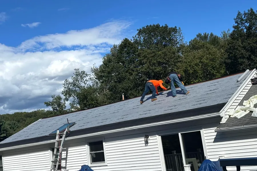 Roofing crew working on asphalt shingles